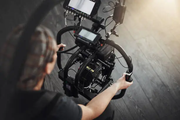 Opérateur tenant une caméra sur stabilisateur gimbal avec moniteur.