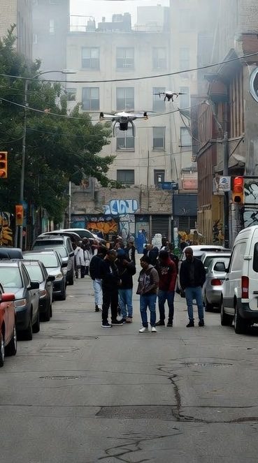 Deux drones survolent une foule dans une rue de la ville.