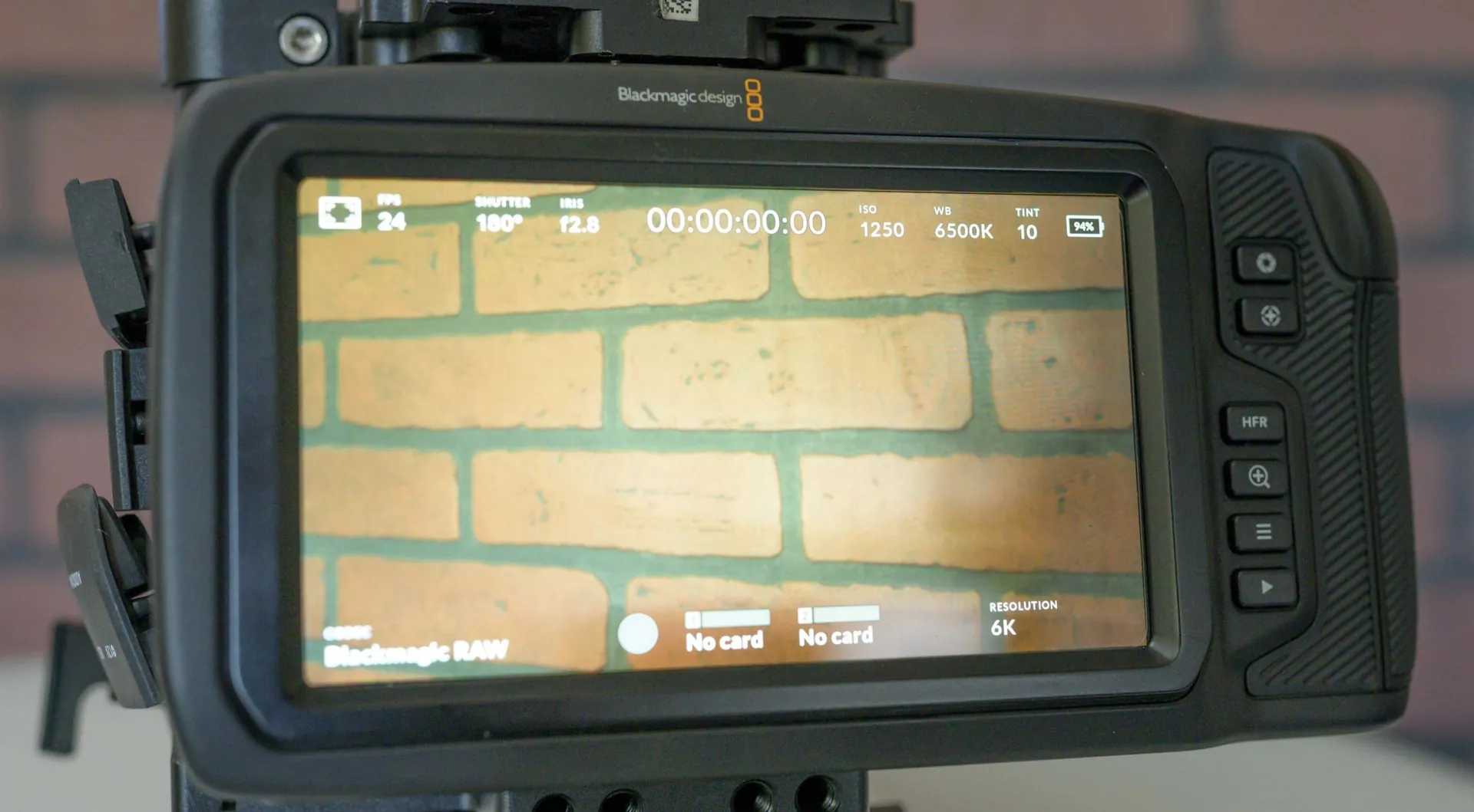 Grand écran tactile arrière de la Pocket 6K Pro affichant l'interface d'enregistrement, devant un mur de briques.