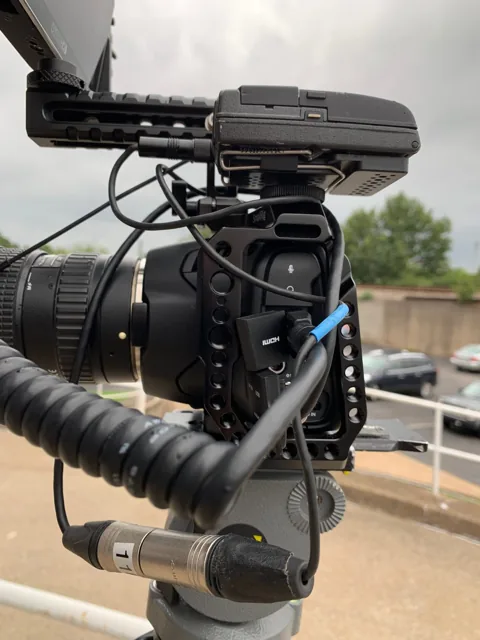 Pocket 6K Pro en cage sur trépied à l'extérieur, avec moniteur, poignée et câble audio XLR.